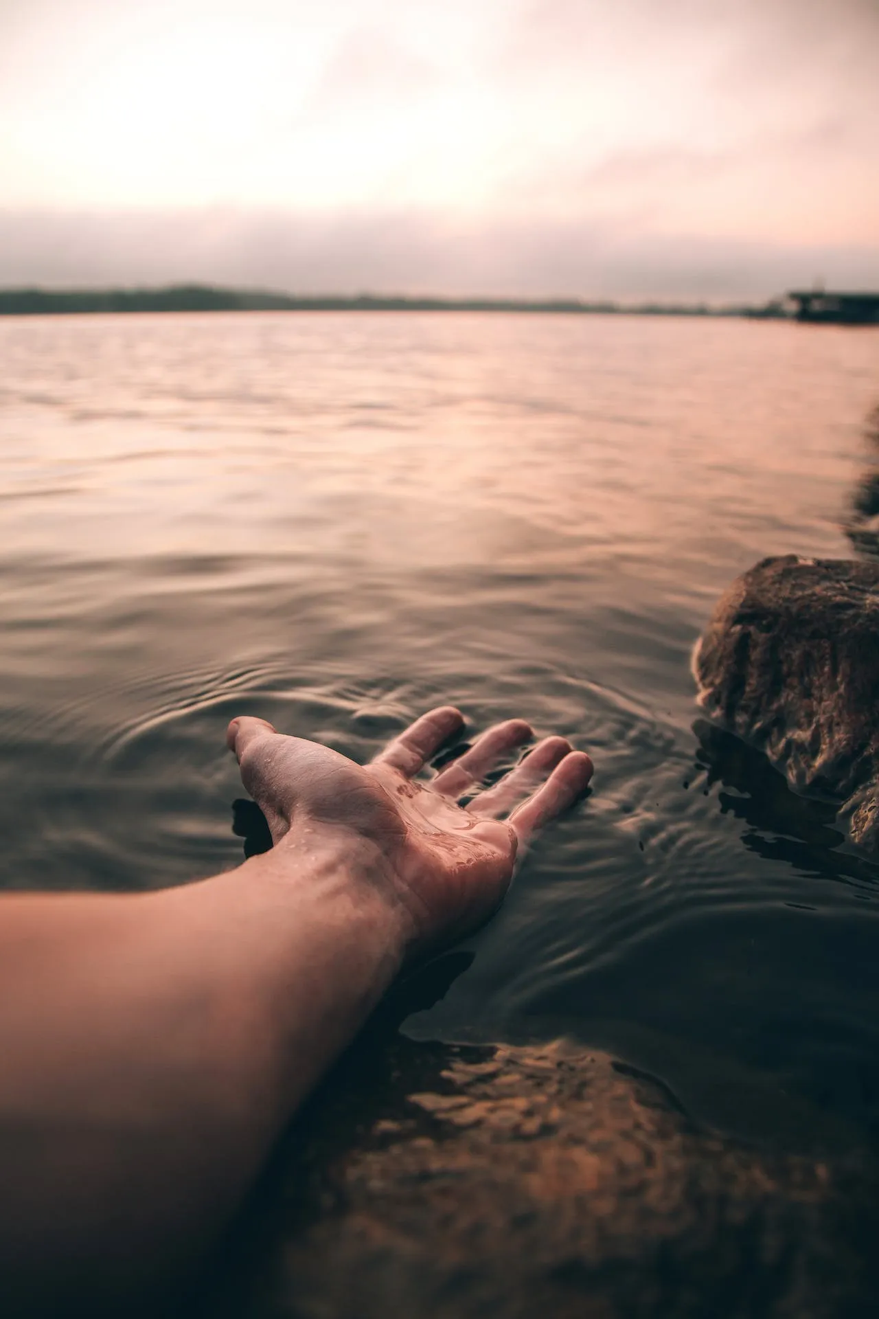Gentle hands placed over water, evoking healing touch